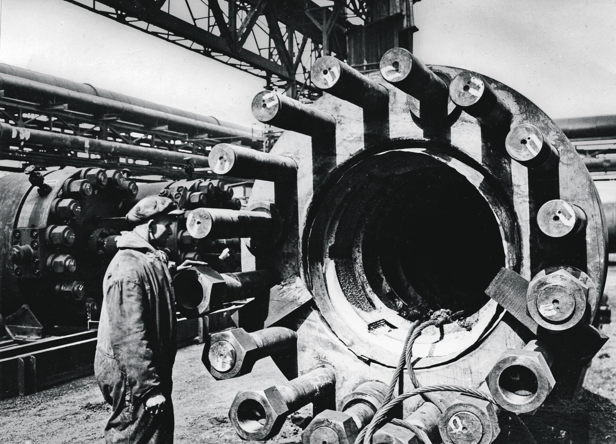 pracovník sotjí zády k fotografovi u obrovského chemického potrubí
