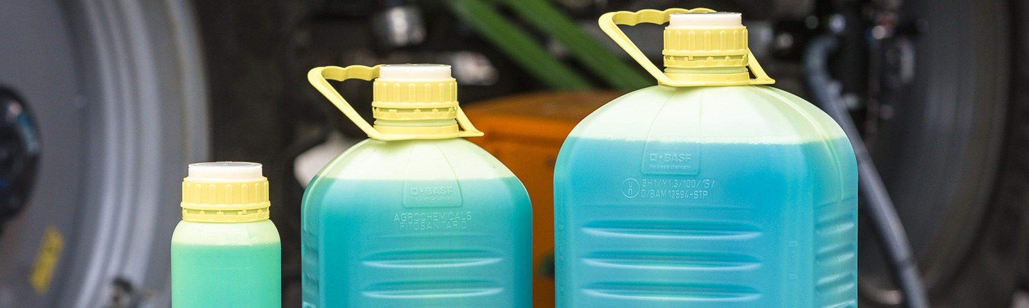 kanystry od BASF s modravou tekutou náplní vyskládané před kolem traktoru